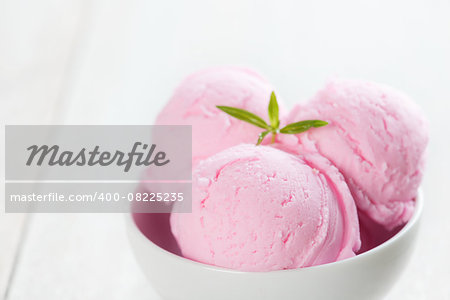 Scoops strawberry ice cream in bowl on rustic wooden vintage table background.