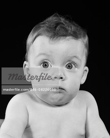 1950s WIDE EYED CHUBBY CHEEK BABY MAKING FUNNY FACIAL EXPRESSION LOOKING AT CAMERA