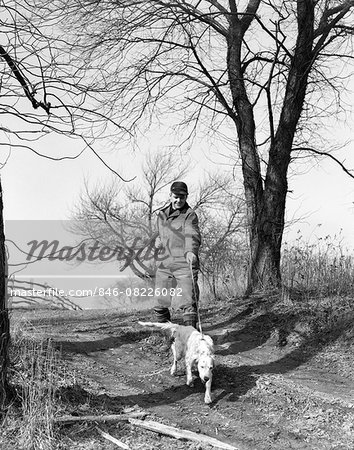 1950s MAN HUNTER WITH SHOTGUN AND ENGLISH SETTER DOG ON LEASH