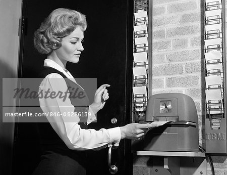 1960s WOMAN PUNCHING TIME CLOCK AT WORK