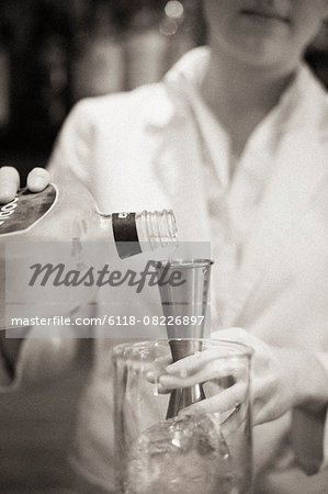 A woman mixing a cocktail, a mixologist at work.