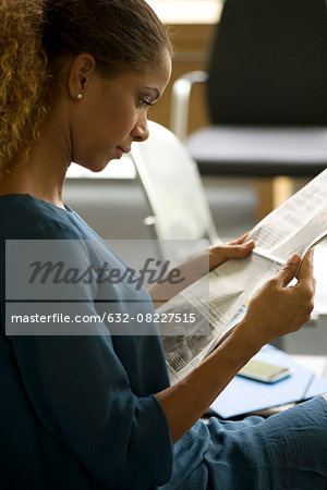 Woman reading newspaper in waiting room