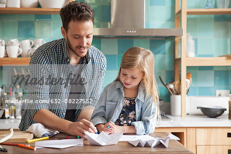 Father and young daughter drawing in kitchen