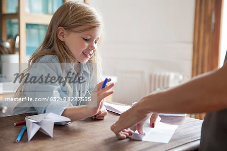 Little girl learning how to make paper airplane