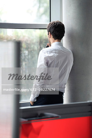Man using phone looking out window