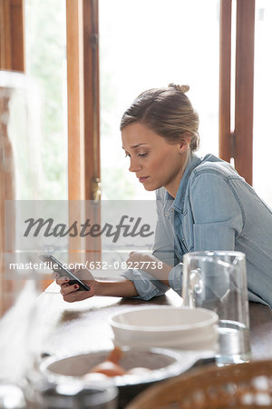 Young woman using smartphone in kitchen