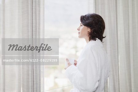 Woman in bathrobe looking out window