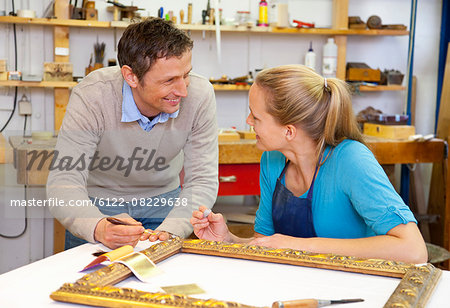 Carpenter and assistant working in shop
