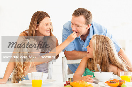 Girl feeding father at breakfast table