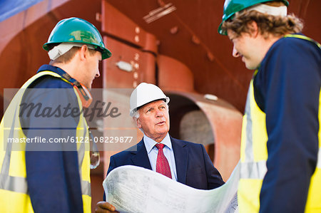 Workers reading blueprints on dry dock