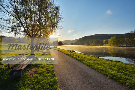 Cycle Path with Bench and Sun in the Morning on River Main, Collenberg, Churfranken, Spessart, Miltenberg-District, Bavaria, Germany Cycle Path with Bench and Sun in the Morning on River Main, Collenberg, Churfranken, Spessart, Miltenberg-District, Bavaria, Germany