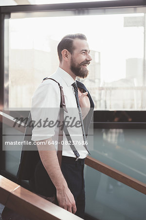 Stylish businessman carrying jacket moving down city stairway