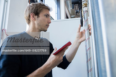 Factory technician using digital tablet to monitor pipes