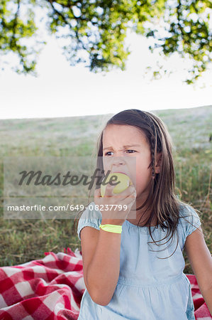 Girl eating green apple at park picnic