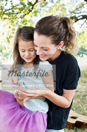 Mature woman and daughter sitting in park eating redcurrants