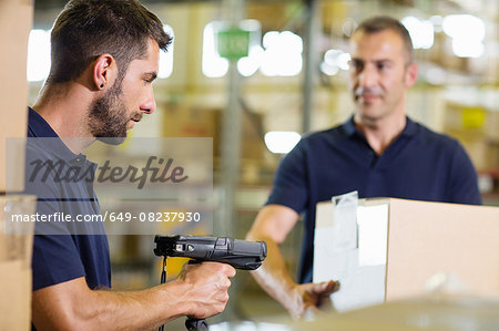 Two warehouse workers using barcode scanner in distribution warehouse