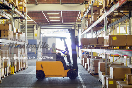 Silhouetted forklift truck at work in distribution warehouse