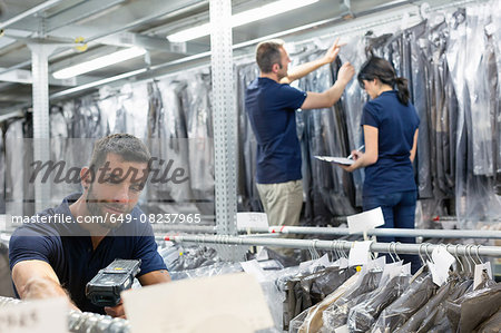 Three warehouse workers preparing garments in distribution warehouse