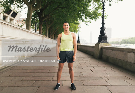 Full length portrait of male runner holding water bottle