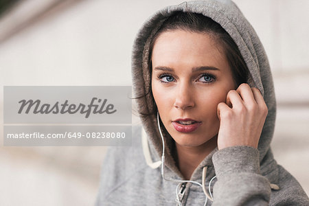 Female runner wearing grey hoody listening to music on earphones