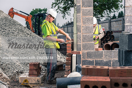 Workers laying bricks on construction site