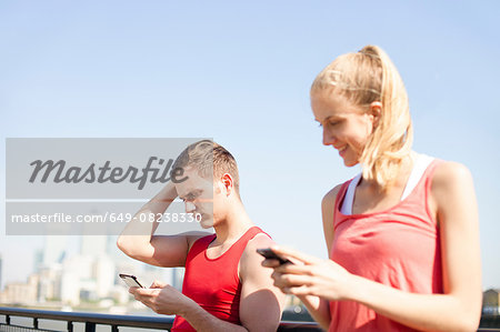 Runners using smartphone on bridge