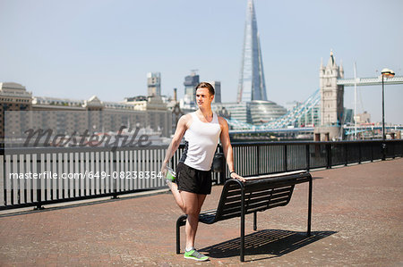 Runner stretching on riverfront, Wapping, London