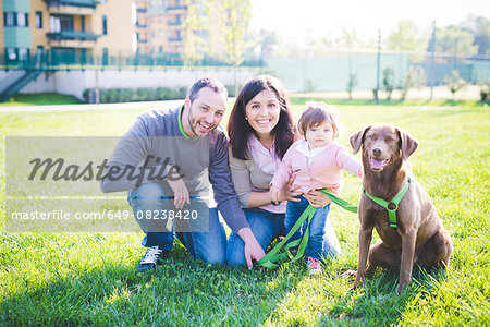 Portrait of mid adult couple with toddler daughter and dog in park