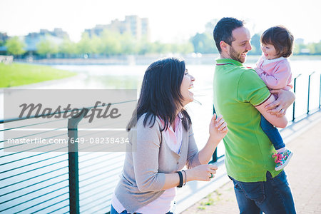 Mid adult couple with toddler daughter at riverside