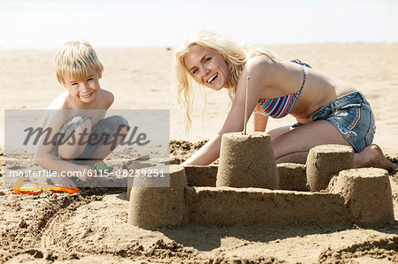 Mother and son making sandcastle on beach