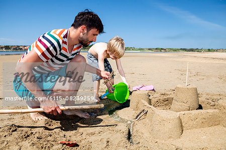 Father and son on beach making sandcastle