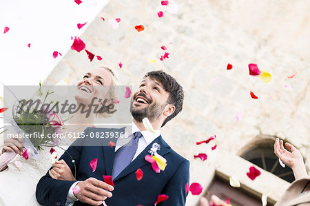 Bride and groom looking at falling rose petals