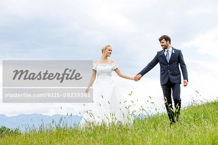 Bride and groom holding hands in the meadow