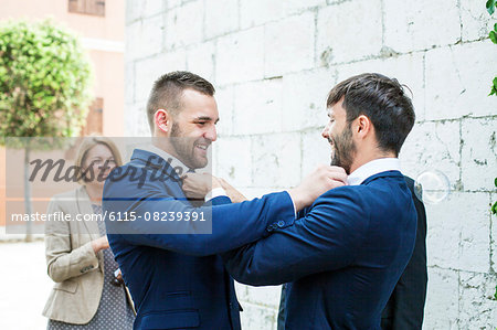 Groom and friend adjusting bow ties of each other