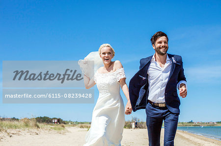 Bride and bridegroom on beach having fun