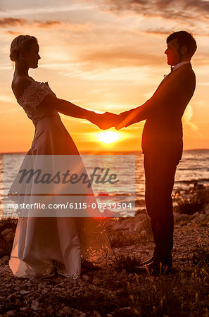 Bride and bridegroom holding hands at sunset