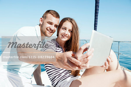 Young couple using digital tablet on sailboat, Adriatic Sea