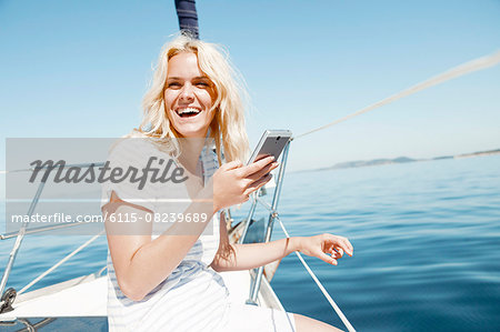 Young woman using smart phone on sailboat, Adriatic Sea