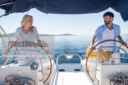 Young couple steering together on sailboat, Adriatic Sea