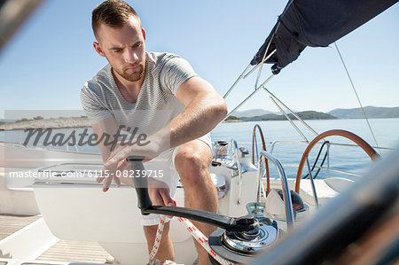 Man turning on cable winch on sailboat, Adriatic Sea