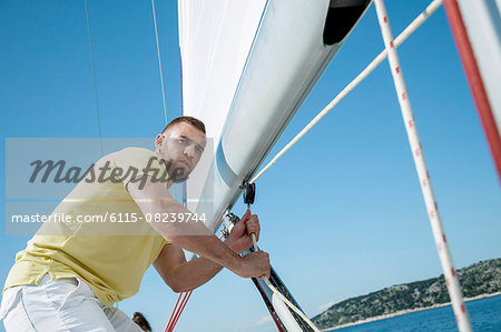 Man adjusting sail on sailboat, Adriatic Sea