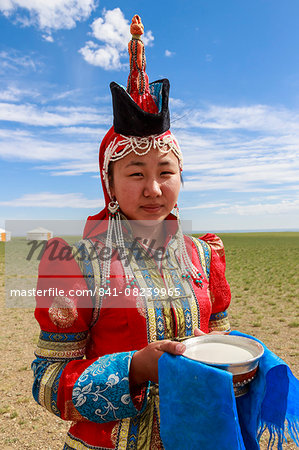 Woman in red deel and pointed hat with silver bowl of milk to welcome visitors, Gobi desert, near Bulgan, Omnogov, Mongolia, Central Asia, Asia