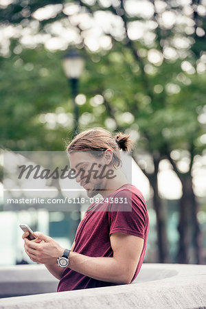 A young man in a park checking his cell phone