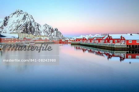 Pink sunset over the typical red houses reflected in the sea, Svolvaer, Lofoten Islands, Norway, Arctic, Scandinavia, Europe