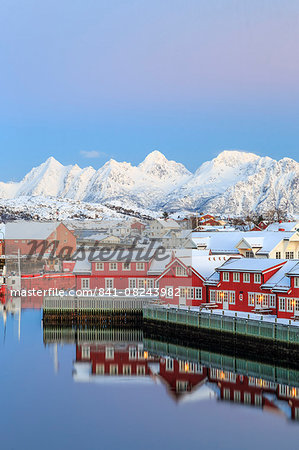 Pink sunset over the typical red houses reflected in the sea, Svolvaer, Lofoten Islands, Arctic, Norway, Scandinavia, Europe