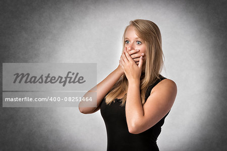 Blonde shocked woman holding anxiously the hand over mouth