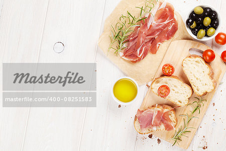 Bruschetta with tomatoes and prosciutto on cutting board. Top view with copy space