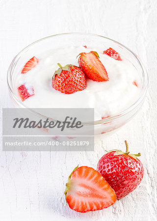 fresh organic yogurt with strawberries on white wooden background