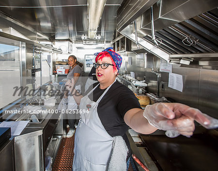 Chef with pink hair directs crew on busy food truck