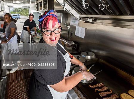 Happy pink haired chef grills bacon on a food truck